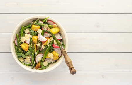 Grilled green asparagus salad with fresh radish, arugula, potatoes, and parmesan cheese. Plant based...