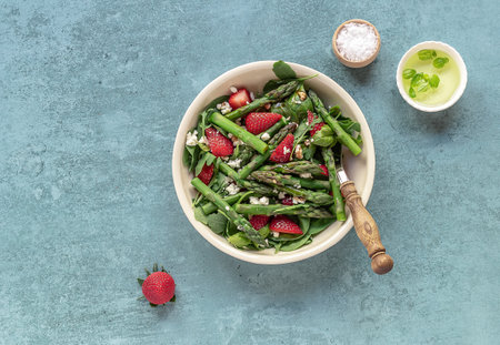 A healthy and delicious salad made from fresh strawberries, green asparagus, feta cheese with vegetable leaves. Vegetarian seasonal food. Detox diet meal.の写真素材