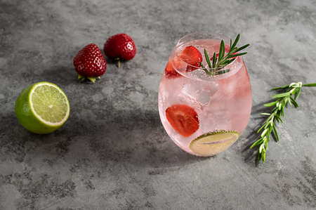Premium pink gin with strawberry, lime, and rosemary. Refreshing alcohol cocktail with ice.の写真素材