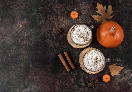 Pumpkin spice latte in a glass mug with cinnamon, nutmeg, and whipped cream. seasonal, autumn drink. top view, copy spaceの写真素材