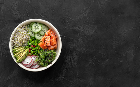 Keto diet poke bowl with salmon, avocado, and edamame beans. over dark background. Banner, top view, copy space.の写真素材