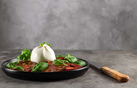 Buffalo burrata cheese served with fresh tomatoes and basil leaves. Delicious Italian appetizer. copy space.の写真素材