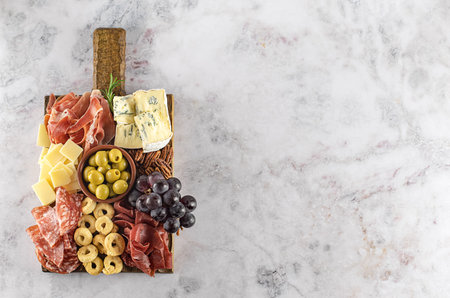 Charcuterie board or Italian antipasti. Assortments of meat and cheese snacks with olives, grapes,...