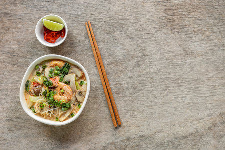 Bowl of curry laksa, a spicy glass noodle dish popular in Southeast Asia with prawns, bok choy, lime, ginger, and chili. Most variations of laksa are prepared with a rich and spicy coconut soup.の写真素材