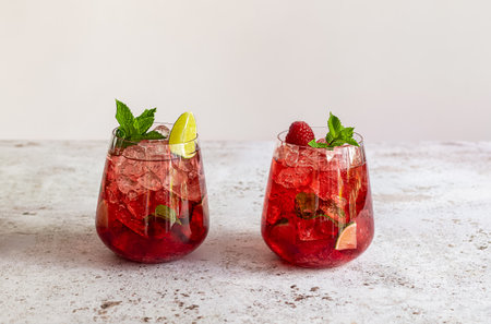 Fresh summer lemonade with raspberry, lime, soda water, and ice in glasses. Cold refreshing drink, cocktail or mocktail.の写真素材
