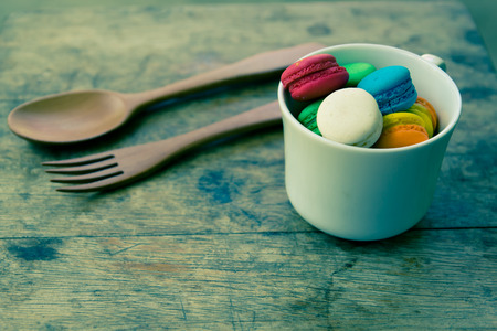 colorful macarons in a cup of tea on wood table process with vintage styleの写真素材