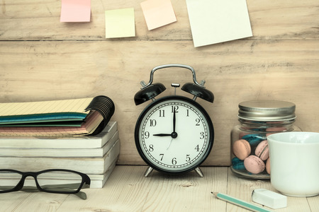 books , glasses, clock ,macaroons and a cup of coffee on workplace desktopの写真素材