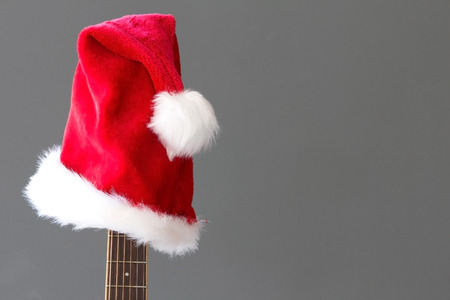 Red Christmas hat on guitar with grey background, Merry Christmasの写真素材