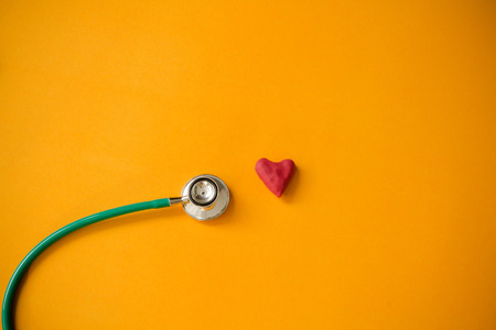Red heart and a stethoscope on yellow backgroundの写真素材