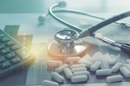 A medical stethoscope and pills on paper of graph information and calculator , symbol for health care costs or medical insurance ,medical purchasing conceptの写真素材
