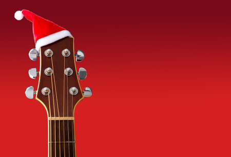 Red Christmas hat on guitar with red background, Merry Christmas songの写真素材