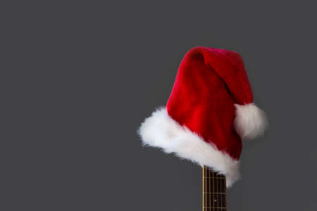 Red Santa Christmas hat on guitar with grey background, Merry Christmas songの写真素材