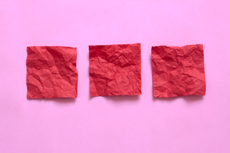 red crumpled sticky note papers on pink backgroundの写真素材
