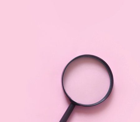 magnifying glass on pink background, flat lay minimal style