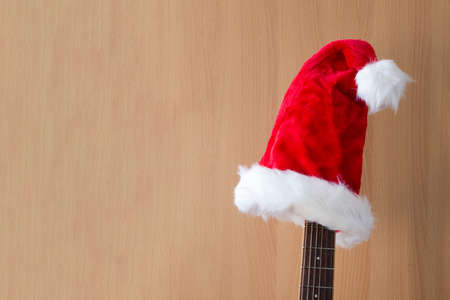 Red Christmas hat on guitar with wood background, Merry Christmas songの写真素材
