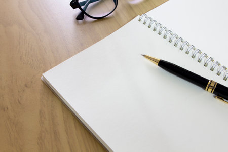 pen on white blank paper page of notebook on wood tableの写真素材