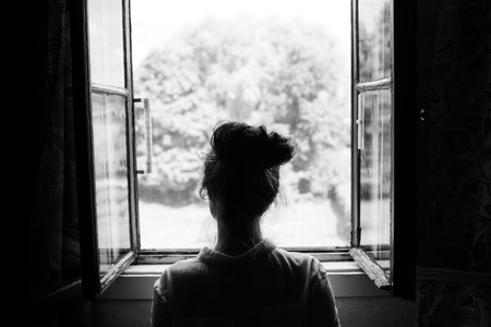Woman looking through the old window on the garden or forest in the countryside. Black and white photography.の写真素材