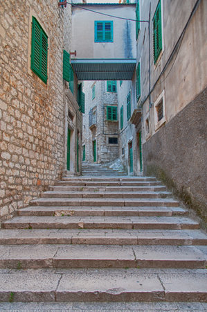 Narrow Mediterranean stair alley with houses windows covered by green wooden shutters.の写真素材