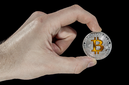 Shining silver and gold metal BTC bitcoin coin holded in hand on black background.の写真素材