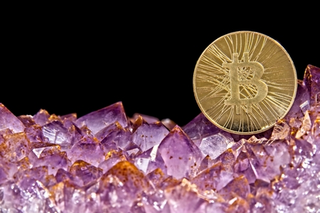 Bitcoin coin on pink Amethyst gemstone crystal geode on black background.の写真素材