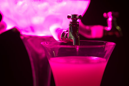 Classic ritual of glass of absinth and dripping water fountain. With pink light.の写真素材