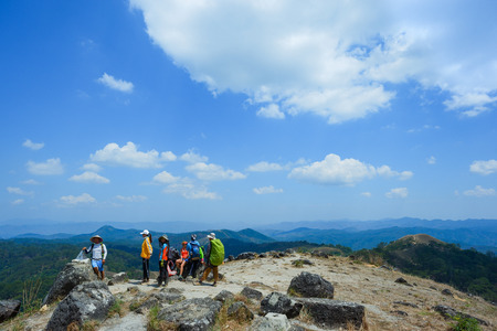 Climbers on the grassy hill. Group of young people walking on a green lawnの写真素材