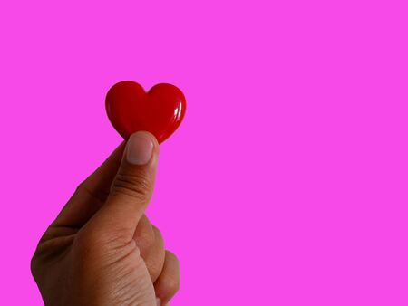 Gift red heart hold in hand. Royalty high-quality free stock images of hands holding gift red heart, health care, valentine, love and family concept, world heart day isolated on pink backgroundの写真素材