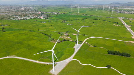 Aerial view of wind turbines on green rice fields in Vietnam. Stock of renewable energy, agriculture...