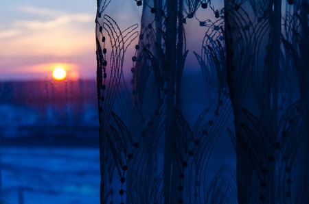 View on sunset from home window with curtainsの写真素材