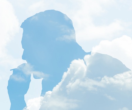 Dramatic double exposure effect on man silhouette with smoke and blue sky with cloudsの写真素材