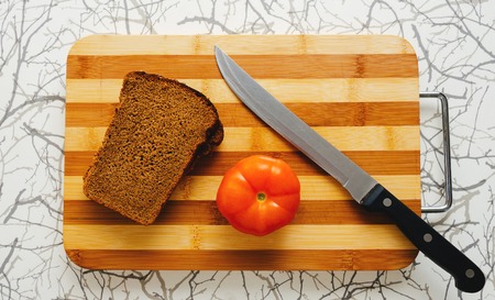 Bread, red tomato and knife on the wood deskの写真素材