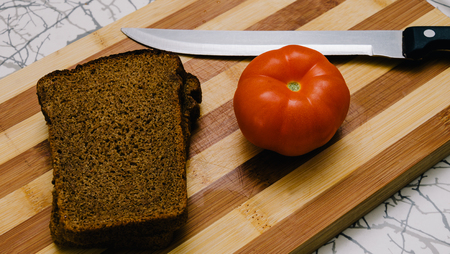 Dark bread and red tomato on the wood deskの写真素材