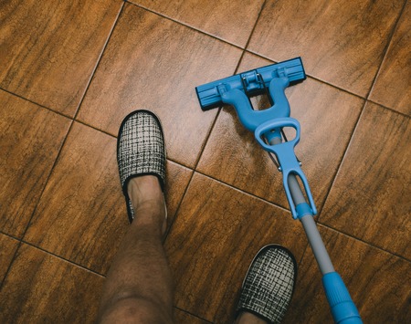 Man leggs, blue mop and kitchen floor on this photoの写真素材