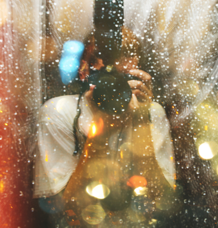 Photo with blurred defocused double exposure effect of the drops on window and cameramanの写真素材