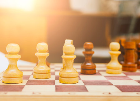 Chess pieces set on a chessboard in the home room or office with beautiful soft sunlight in sunset...
