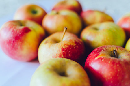 Many apples on the home kitchen table with soft light and selective focus