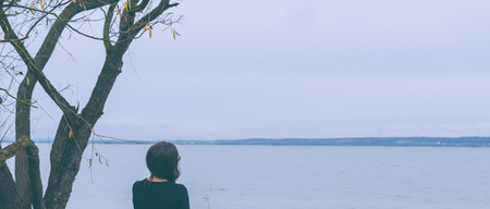 Girl on the lake in dark autumn dayの写真素材