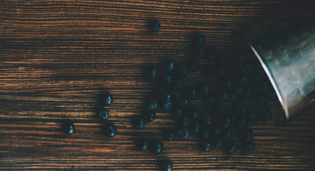 Spill fresh blueberries on table from glass. Wooden background suitable for text.の写真素材