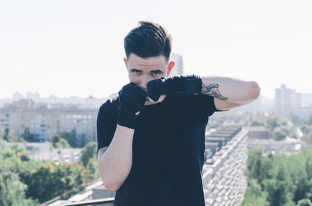 Muscular kickbox or muay thai, boxing fighter. Portrait on the city roofの写真素材