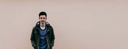 Young beautiful man in jacket on the pink wall background, photo with place for text or other/の写真素材