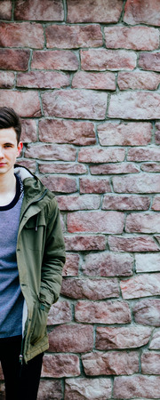 Portrait of the half young man on the old bricks wall backgroundの写真素材