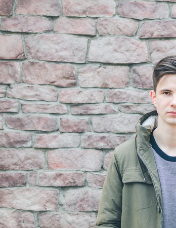 Young man half portrait on the old brick wall backgroundの写真素材
