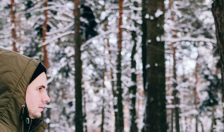 Portrait of the young man in jacket in winter forestの写真素材
