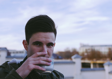 Young man and cup with coffee on the city street, photo with palce for text and otherの写真素材
