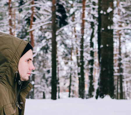 Young man in winter forest after the snowfallの写真素材