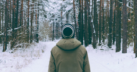 Man in hat on the road in witner forestの写真素材