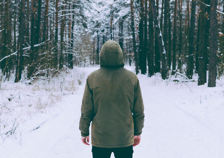 Young man in jacket in the deep winter forestの写真素材