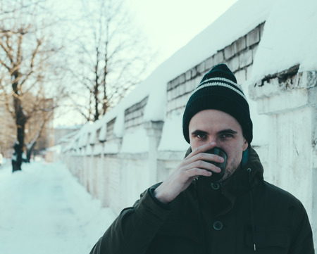 Young man drinking a coffe on the winter streetの写真素材