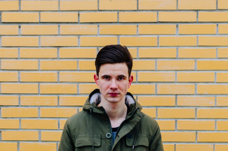 Portrait of the young man on the yellow bricks background