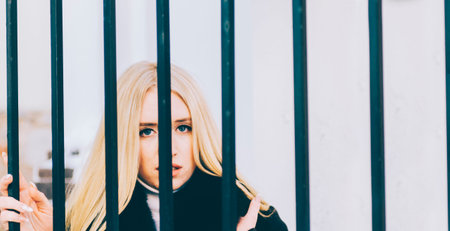 Portrait of a beautiful young blonde woman in autumn vintage scarf near metal grateの写真素材